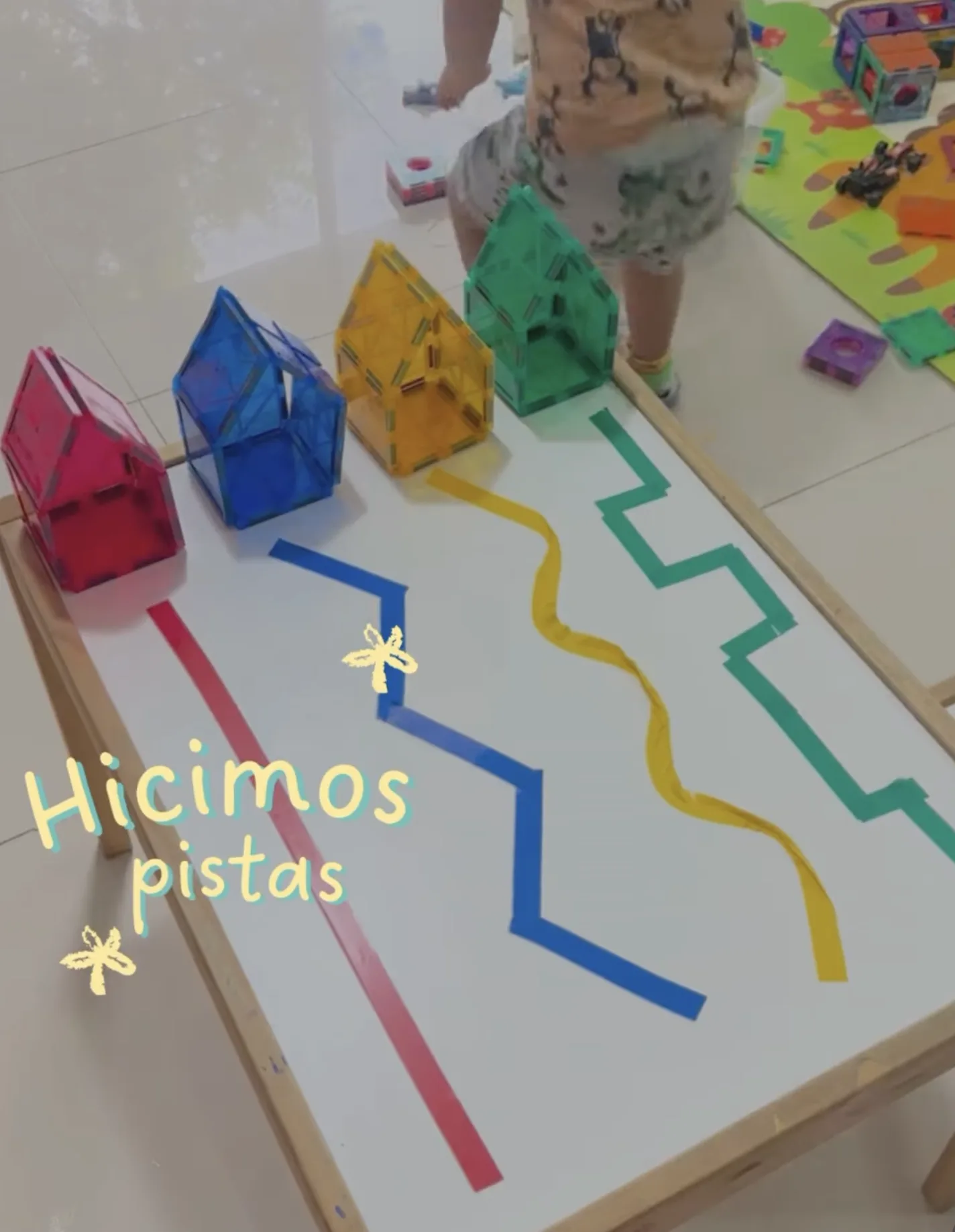 Casas construidas con fichas magnéticas junto a pistas de colores